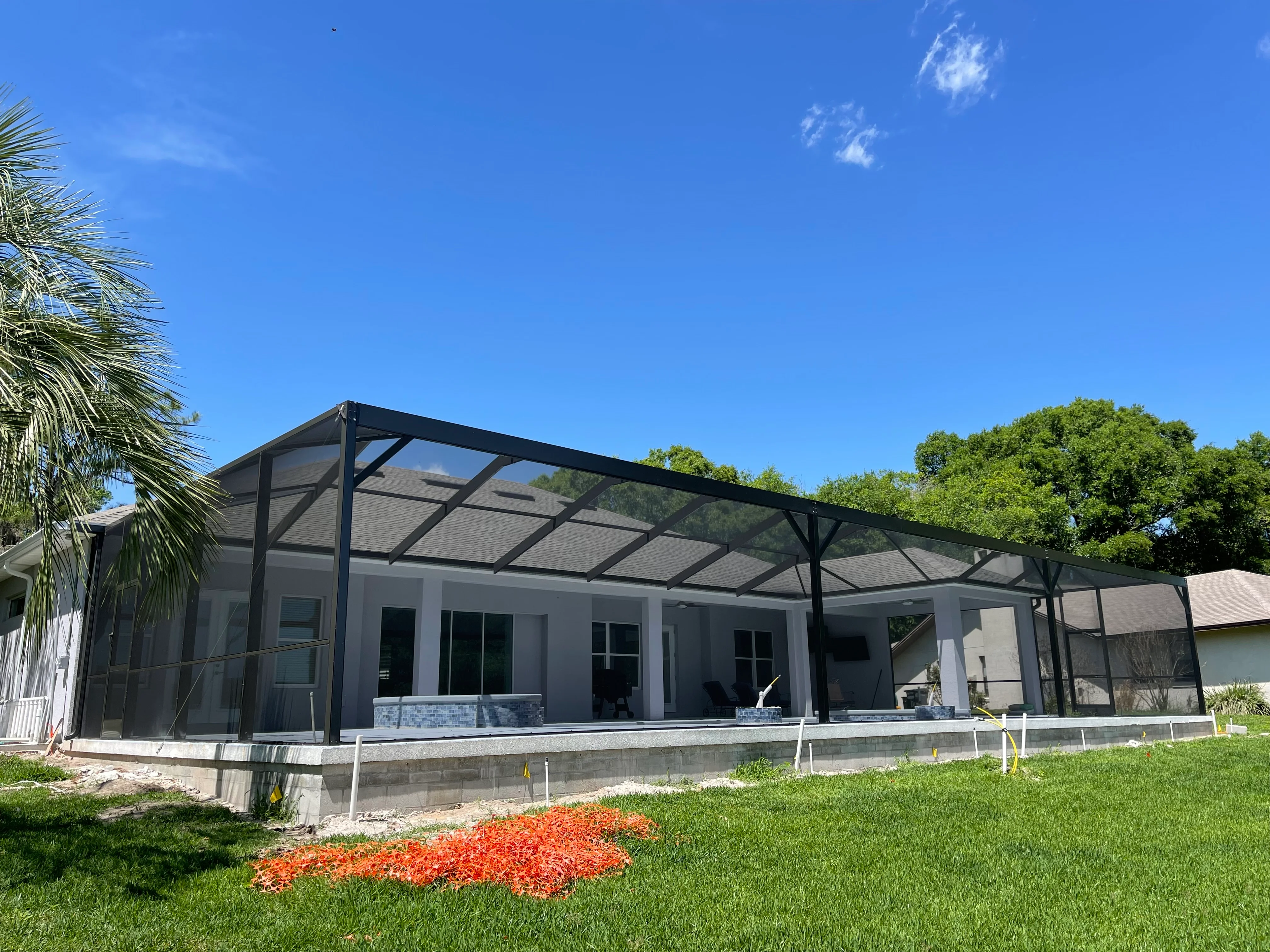 Black aluminum screened patio with mesh panels and glass doors on concrete foundation