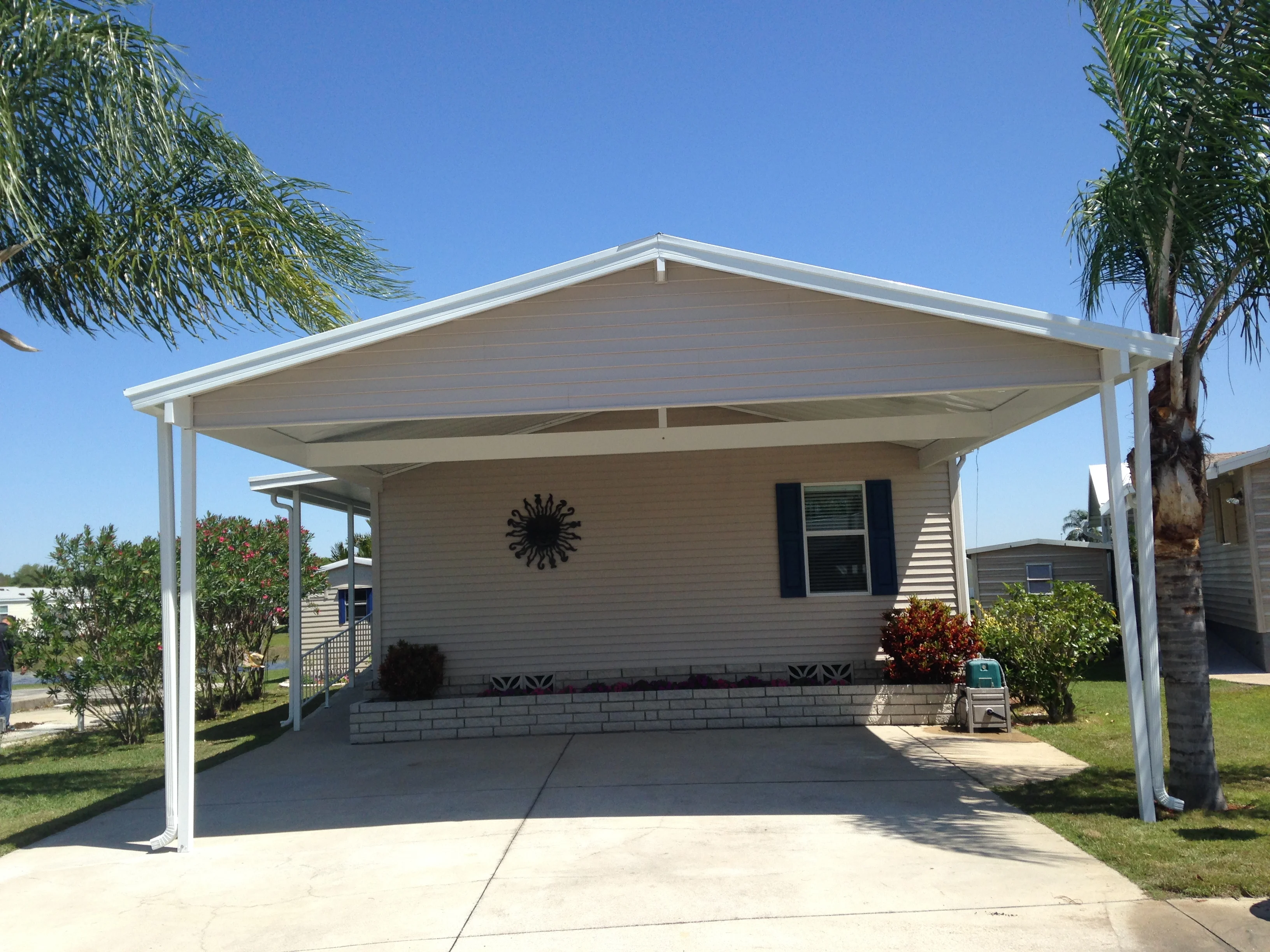White aluminum carport with gable roof over concrete driveway and mobile home