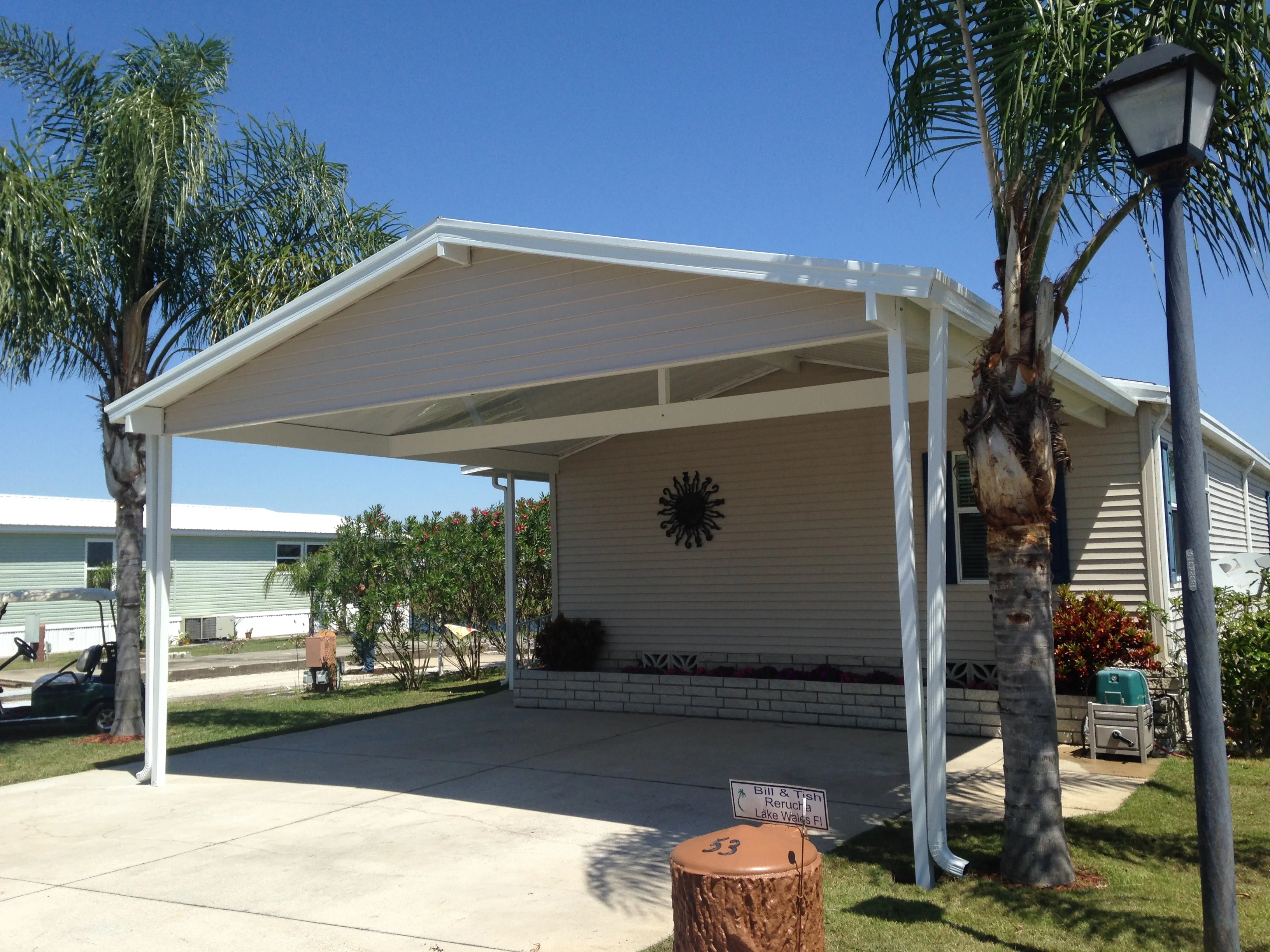 White aluminum patio cover with gable roof over concrete driveway and carport area