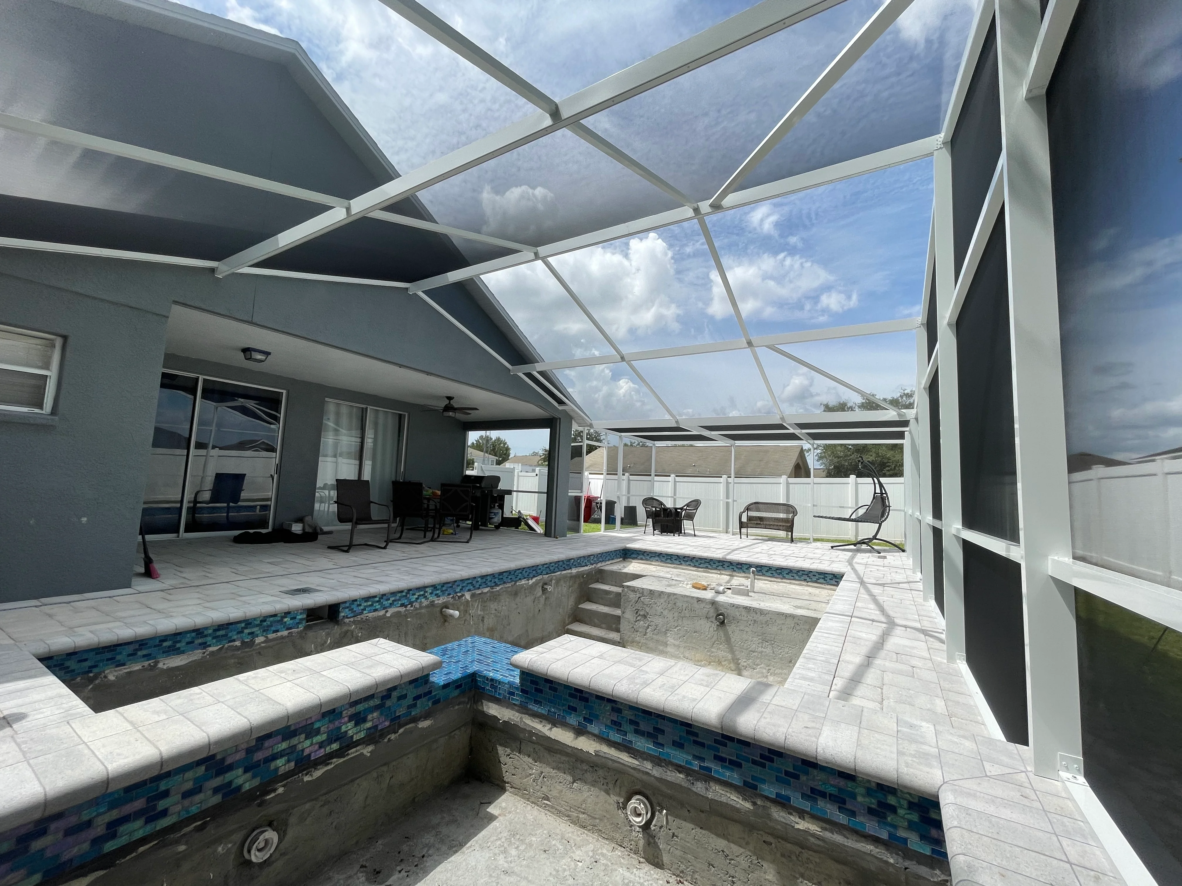 Aluminum patio cover with skylights over pool, blue tile trim, white tile deck