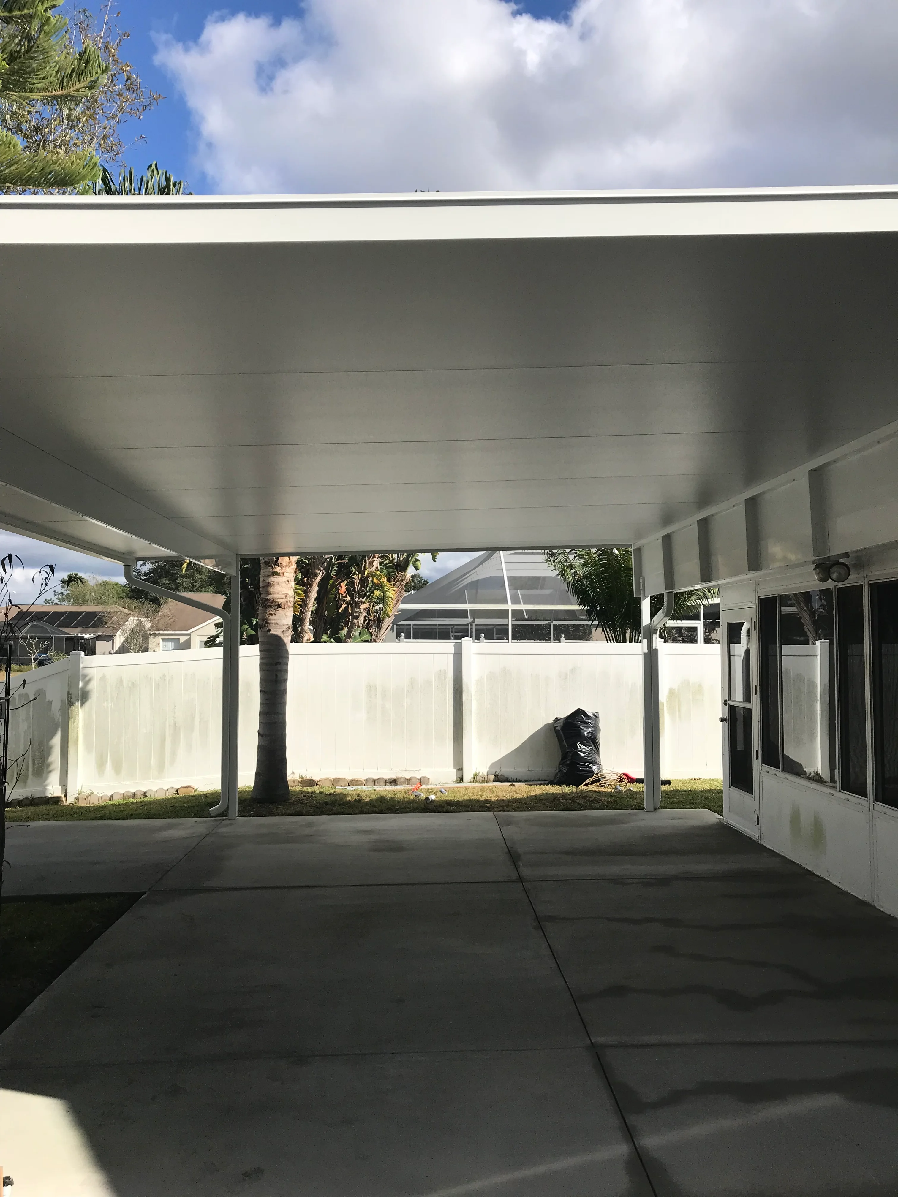 Aluminum patio cover with white vinyl fence and concrete pad