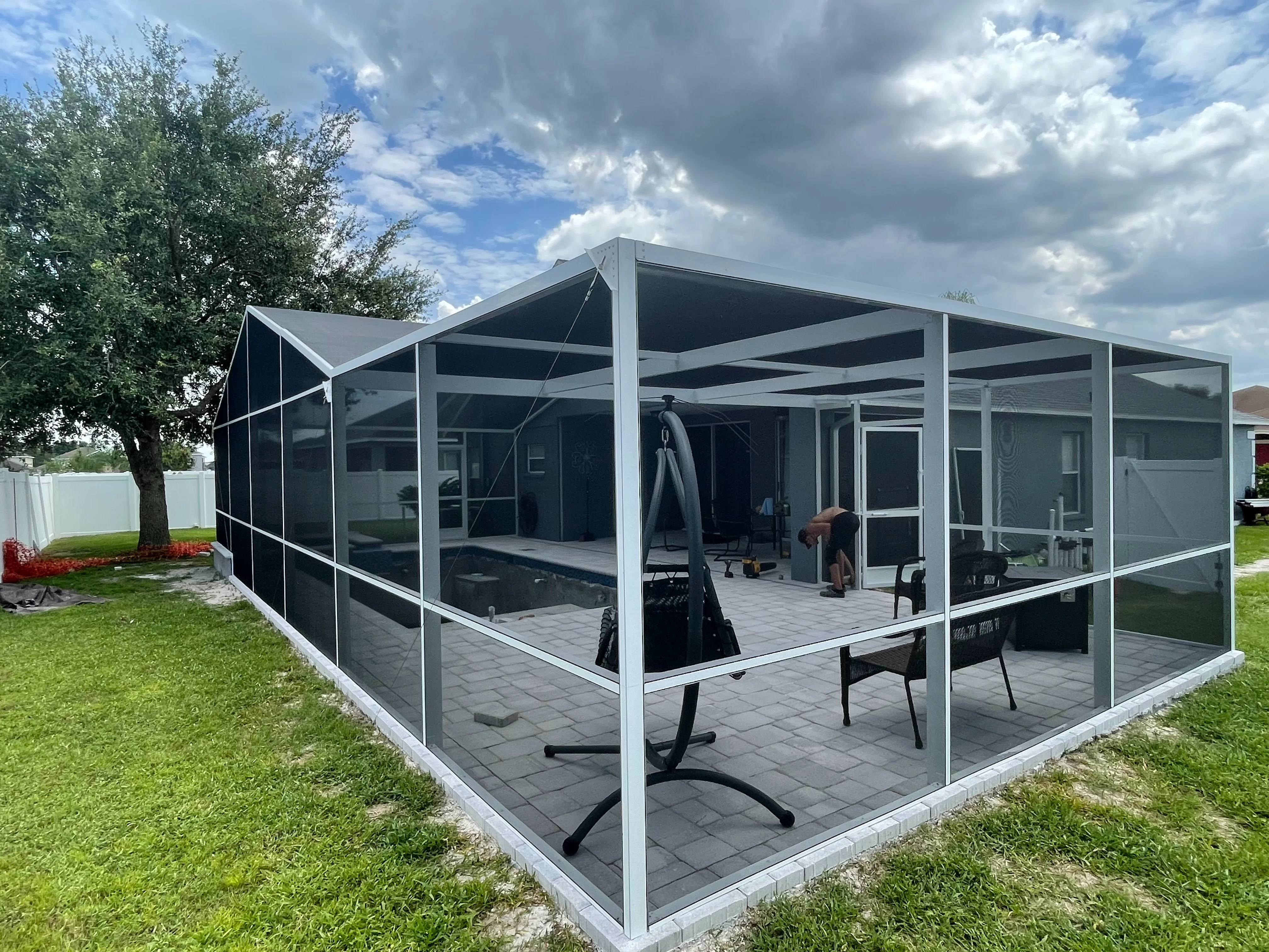 White aluminum framed screened patio with black mesh panels and paver foundation