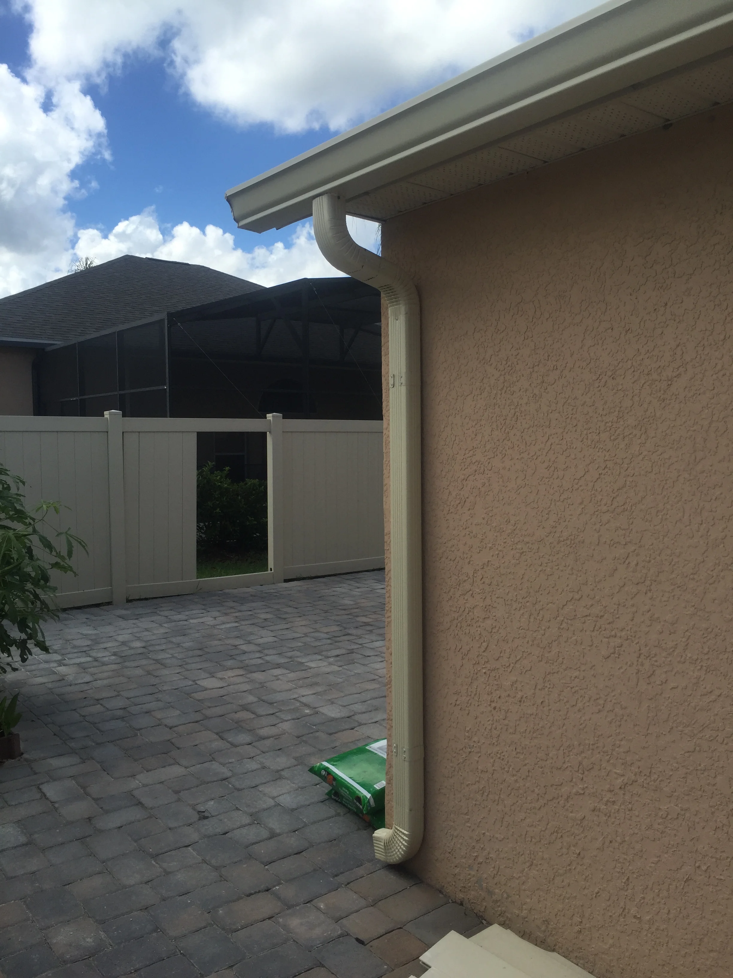 Paver patio with charcoal pavers, white vinyl fencing, and integrated gutters