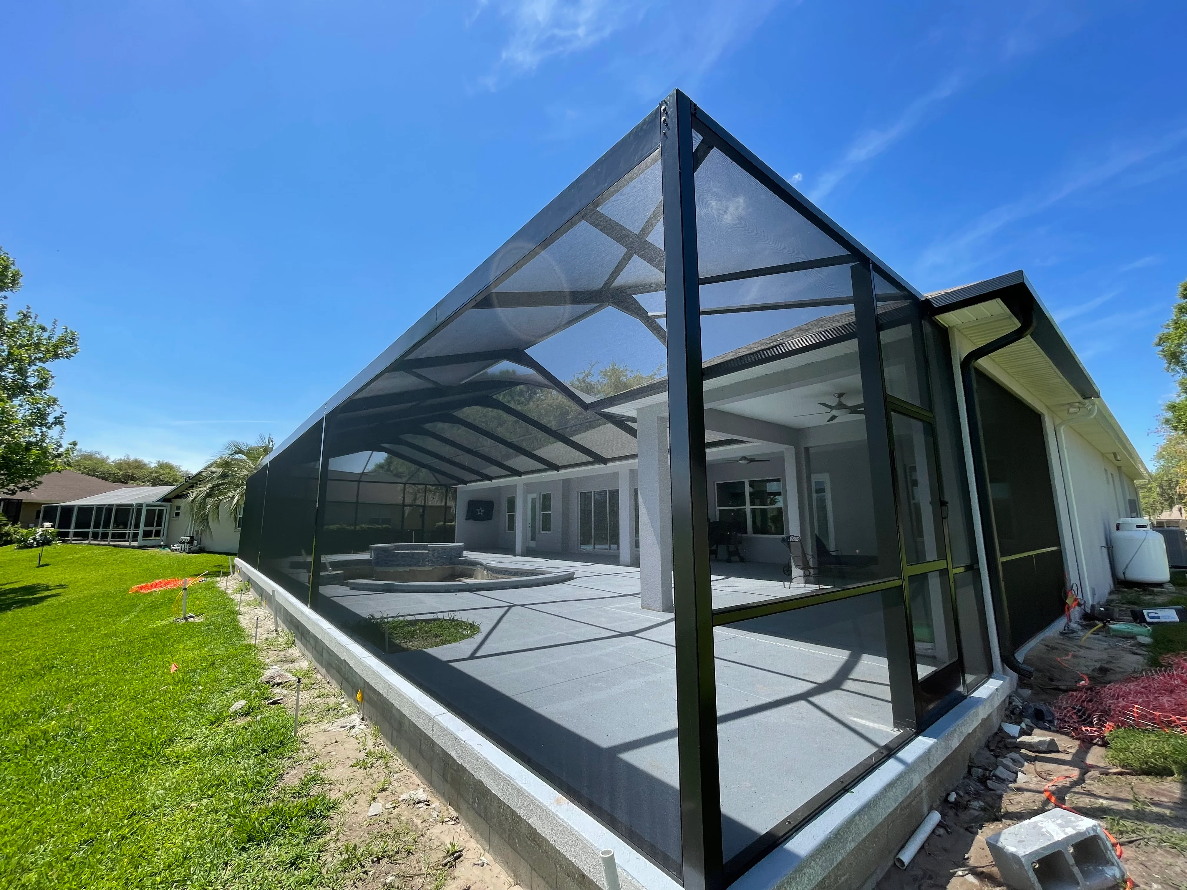 Black aluminum patio enclosure with polycarbonate roof and screen panels attached to home