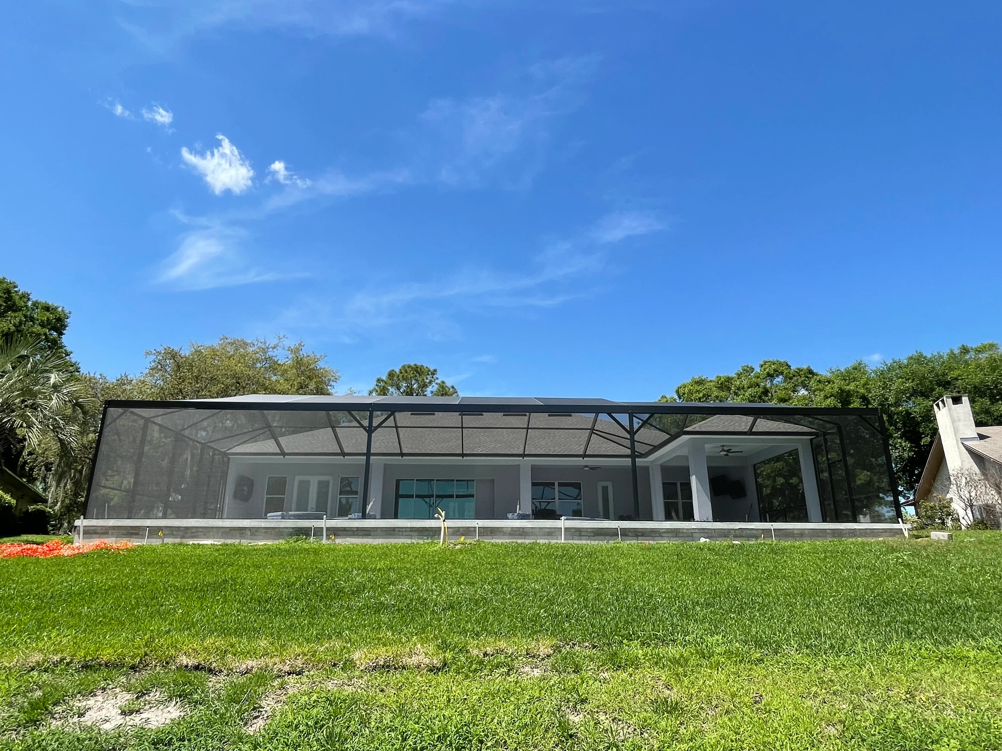 Black aluminum screen enclosure with concrete pad and glass doors on residential patio