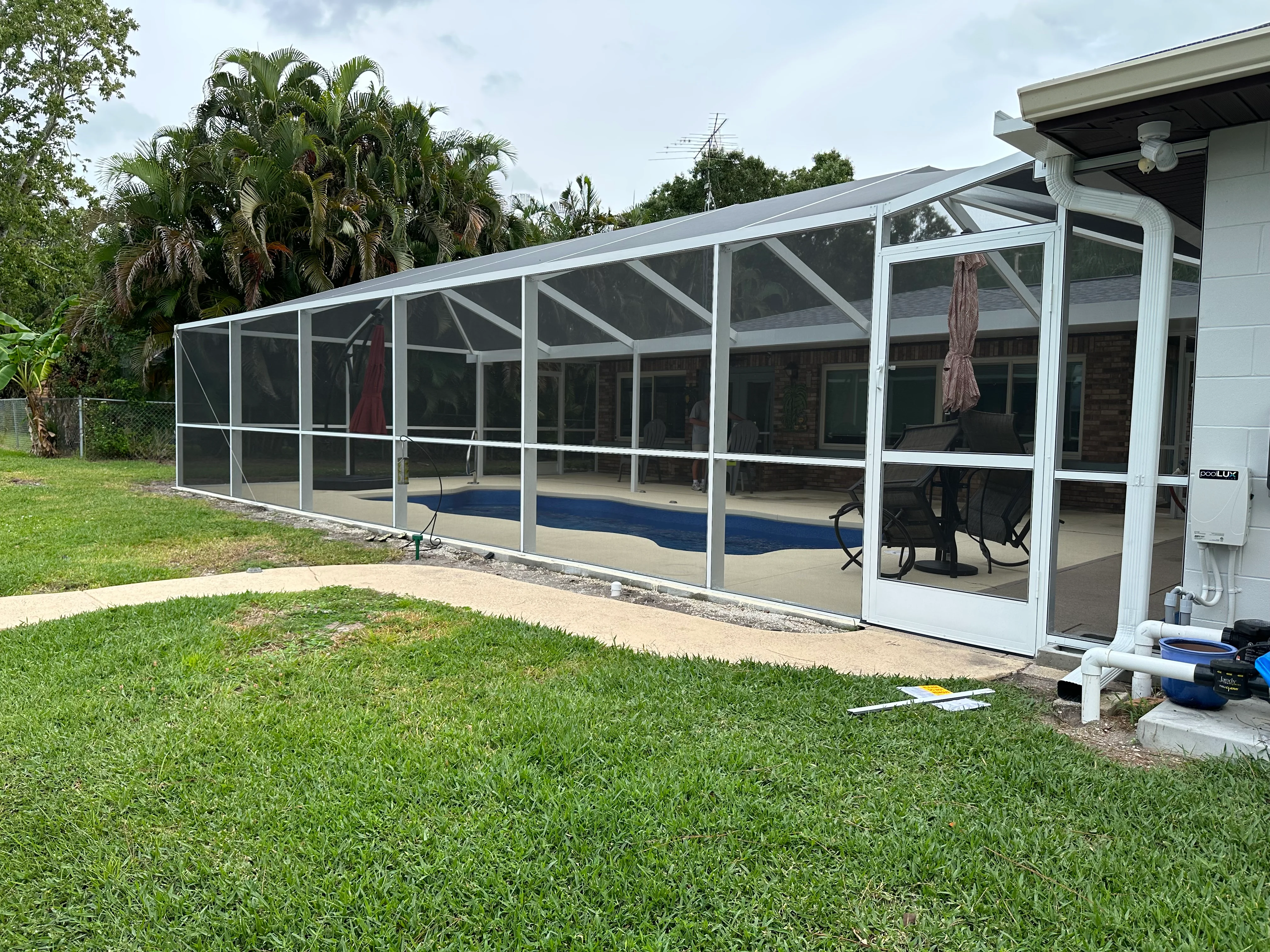 White aluminum screen enclosure with sloped roof, full-length screening panels, and concrete pad foundation