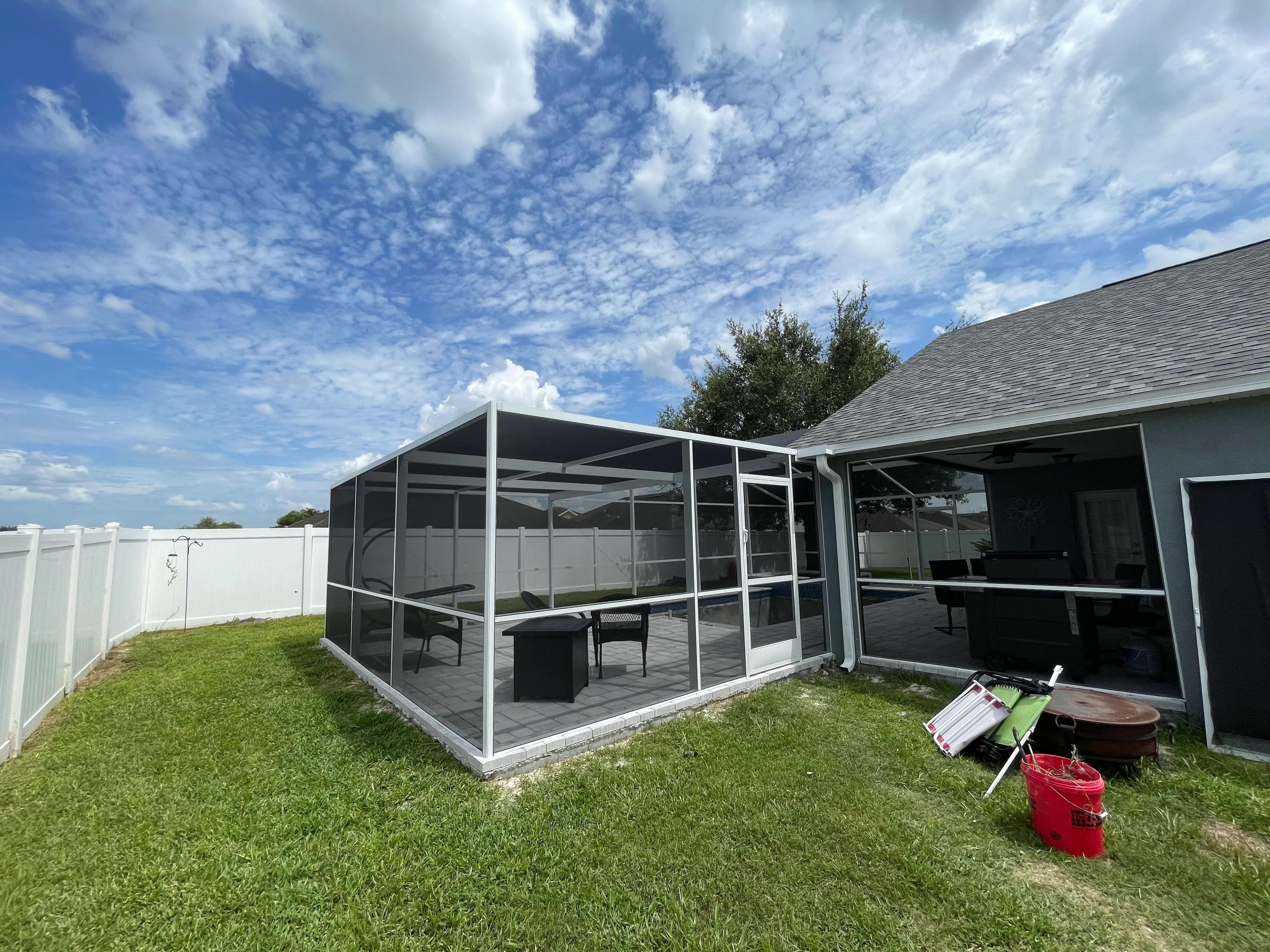 Aluminum-framed screened patio with roof and concrete foundation attached to residential home